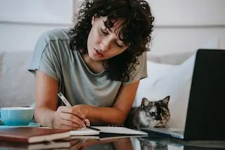 תלמידה עם חתול לומדהת שיעור פרטי באנגלית אונליין עם מורה.