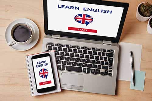 A computer and phone with the British flag with a cup of coffee - ready for an English learning course